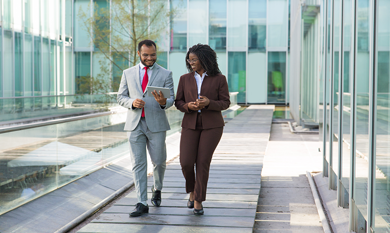 Two business people walking down a corridor talking