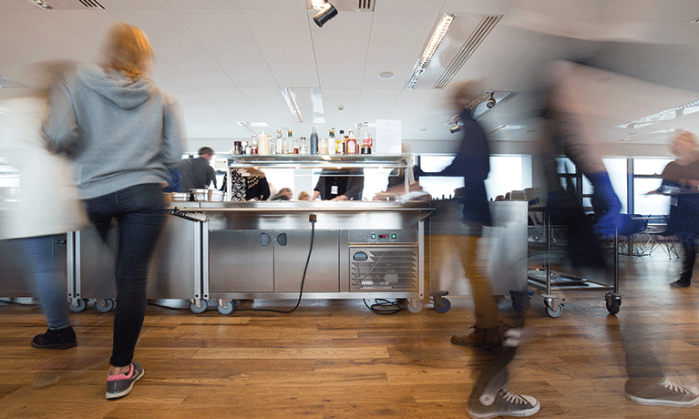 Motion blurred people at lunchtime in a busy canteen