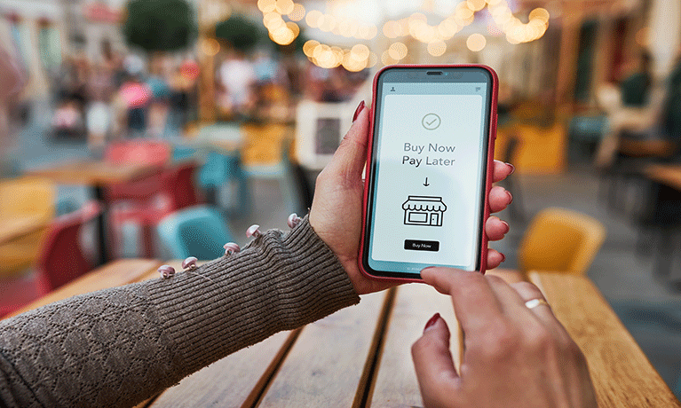 A woman holding up a mobile phone using a Buy Now Pay Later service