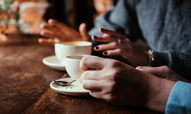 Two women discussing business projects in a cafe while having coffee