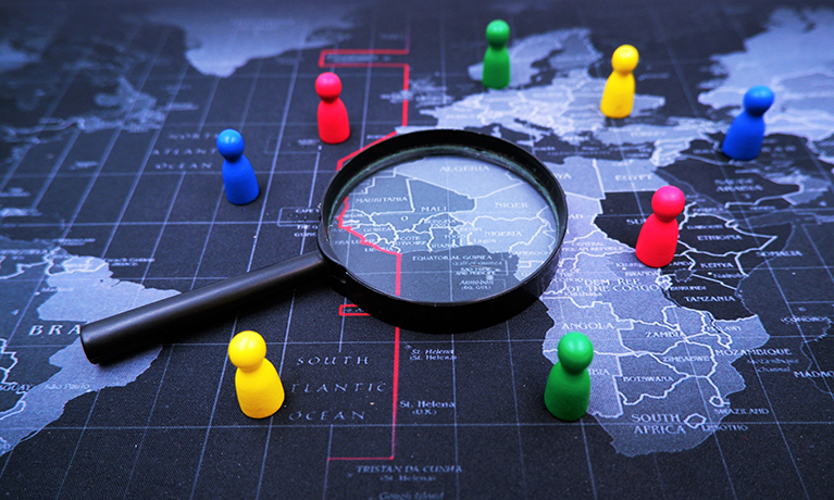 A graphic image of a magnifying glass over a world map