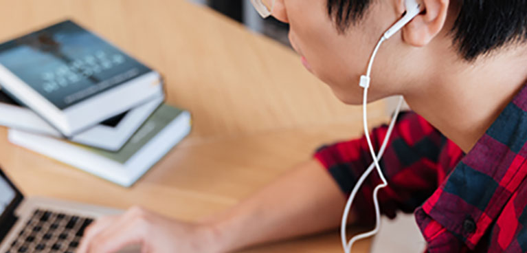 A man wearing headphones works on a laptop. 