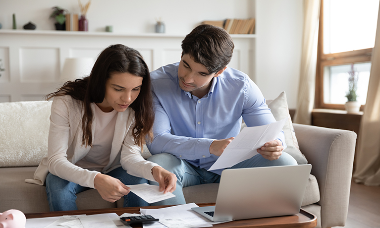 A man and young woman looking at documents and calculating finances