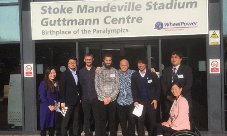 7 delegates stand outside Stoke Mandeviile Stadium.
