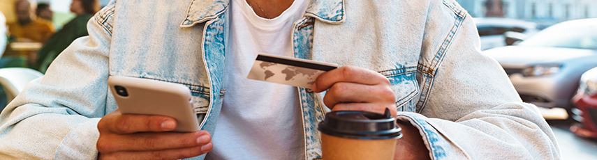 A man looking down at a credit card while holding a mobile phone