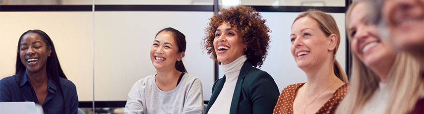 women sitting in a boardroom smiling