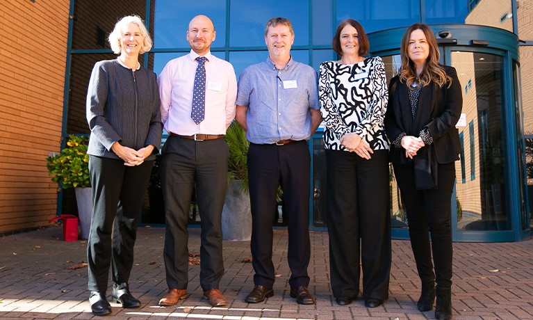 Group of academic staff stood outside university building