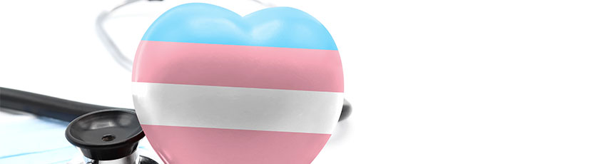 a heart bearing the trans flag sits next to a stethoscope