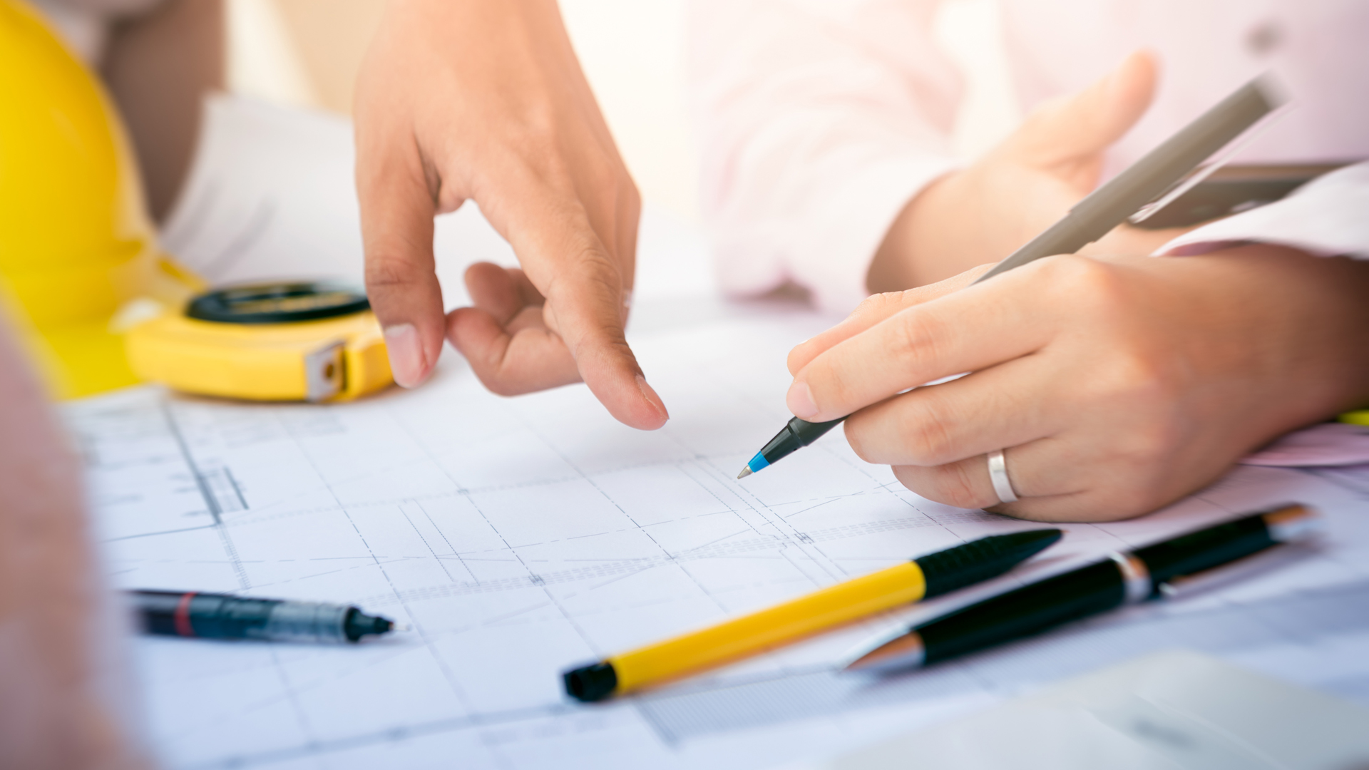 Close up of hands with one pointing and the other holding a pencil making notes