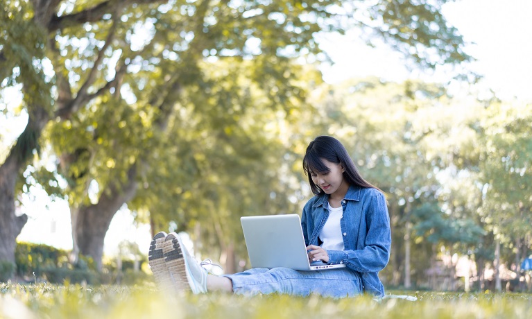 Girl sitting outside on the grass with laptop