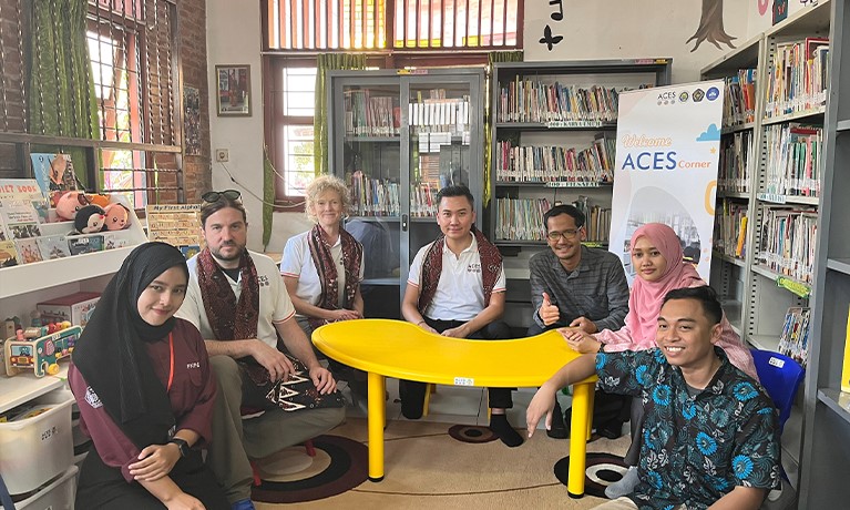 A group of people sat around a yellow table in a room filled with books