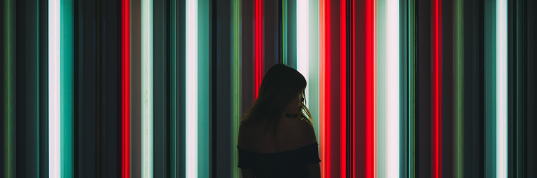 a silhouette of a woman in front of a wall of vertical neon lights