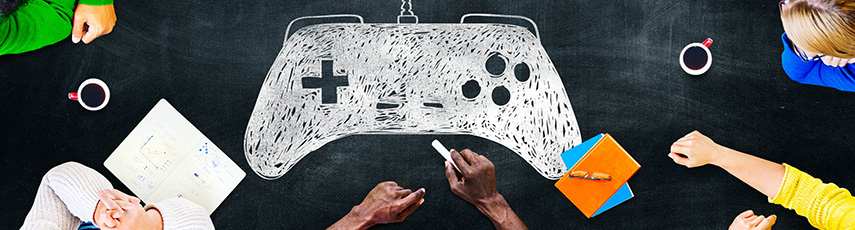 People sitting around a blackboard desk with a chalked game controller on it
