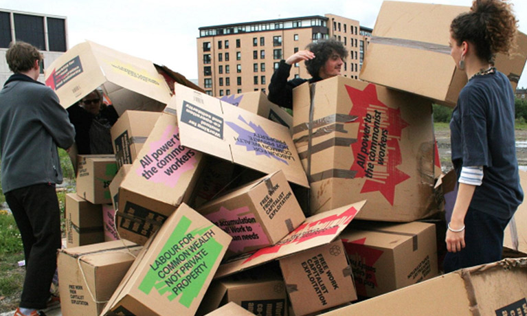 A group of young people build a structure with cardboard boxes