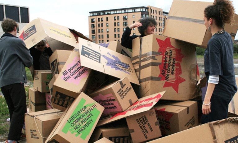 three people building a structure from cardboard boxes