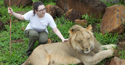 Natasha crouching down next to a lion