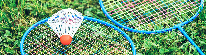 Two badminton rackets and a shuttlecock in the grass