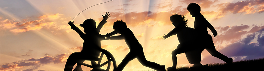 Silhouette of a boy in a wheelchair playing with children against a sunset background