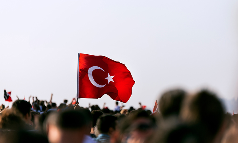 Turkish flag flying above a crowd outside