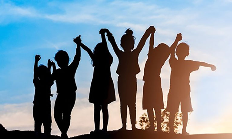 Group of children's silhouettes holding hands up to the sky