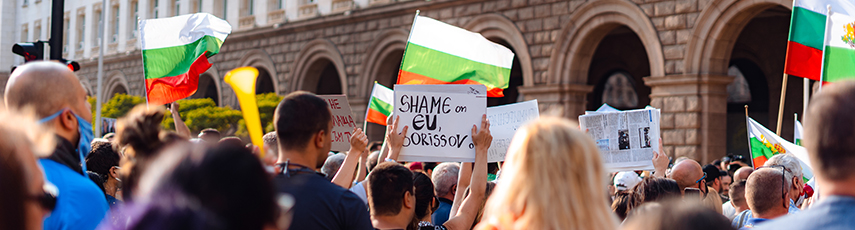 Protestors outside a government building holding signs and flags in Sofia, Bulgaria