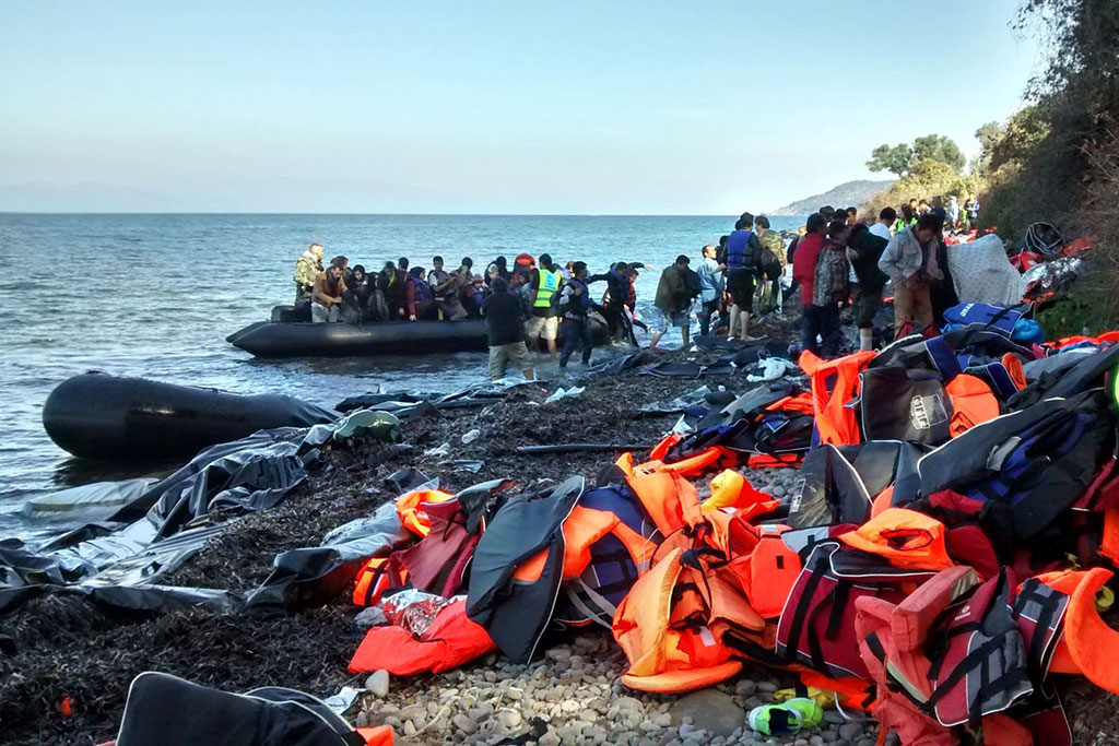 Refugees getting in a boat next to a pile of life jackets