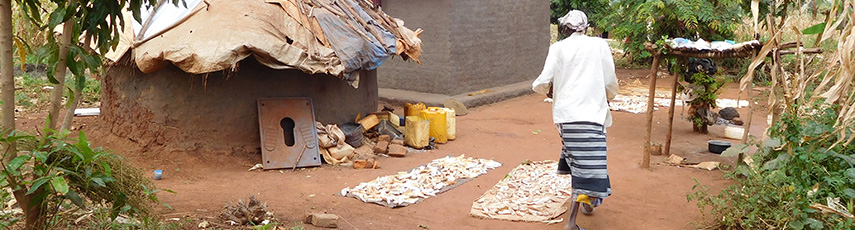 A woman walking by a hut in a refugee camp in Uganda