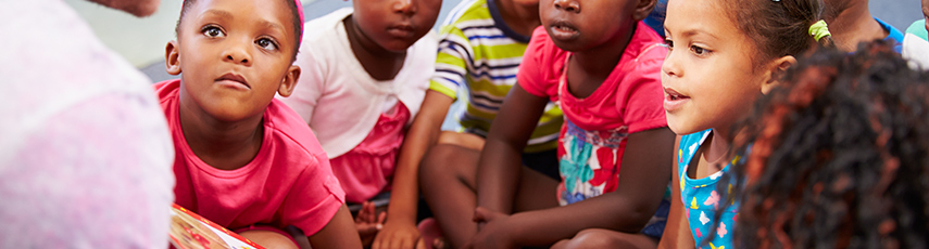 Pre-school children listening to a teacher read from a book