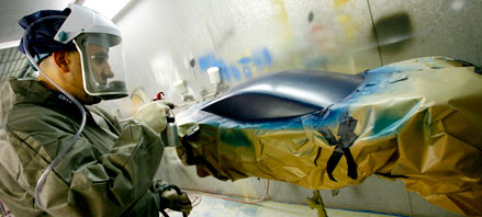 Man wearing protective gear painting a car
