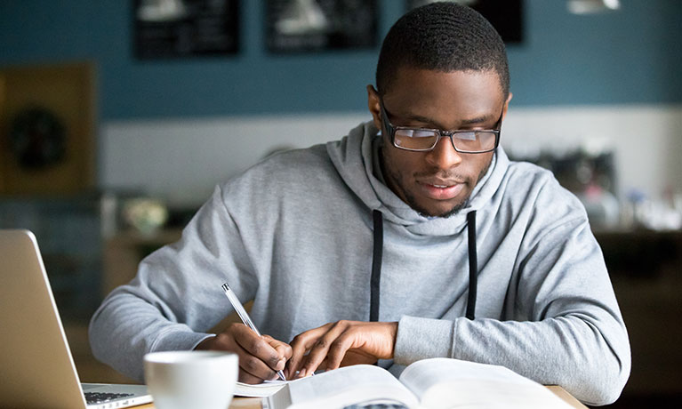 a man writes while reading