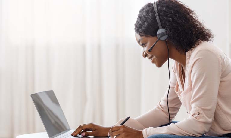 women working on a laptop wearing a headset