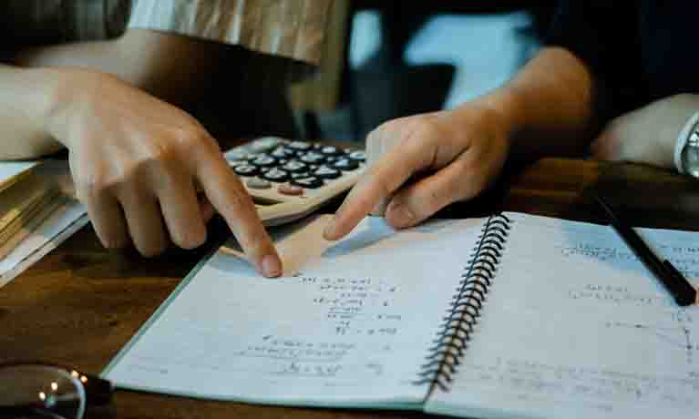 Hands examining calculator and mathematics/statistics book