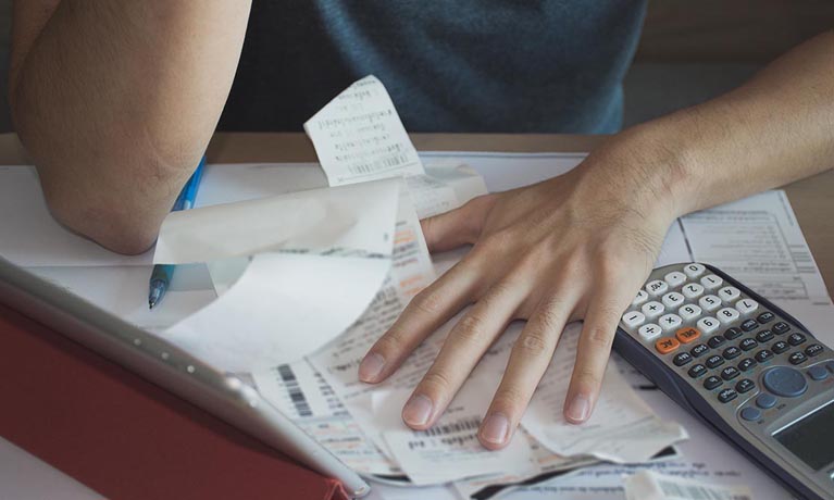 bills spread out of table with calculator and person hands