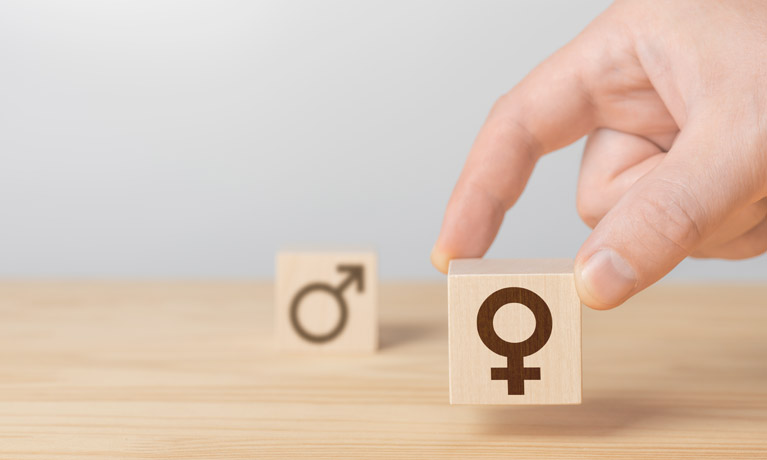 Two small wooden blocks on table with gender symbols printed in black