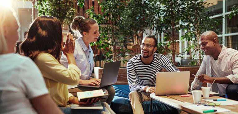 Group of individuals sat around a coffee table with laptops and notebooks