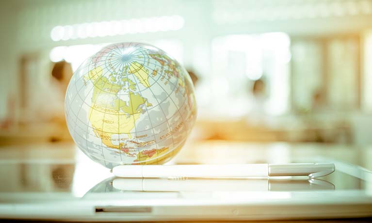 globe on a glass table with tablet and pencil