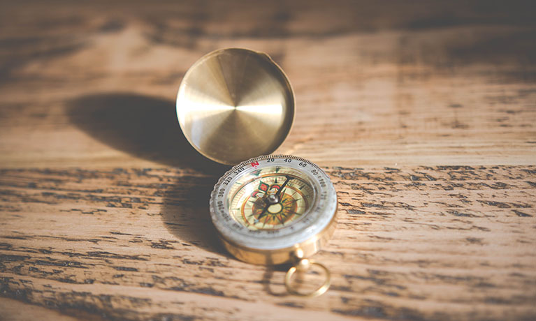 Gold antique compass on wooden table