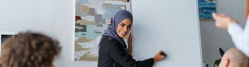 Female Muslim corporate trainer explains to a group of employees