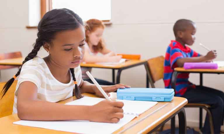 Girl writing at desk in classroom