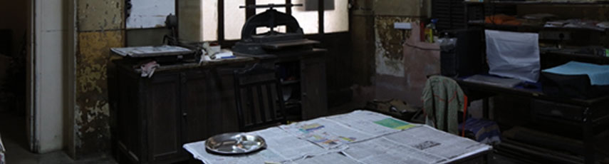 dark room with objects lying around and newspapers scattered around the table