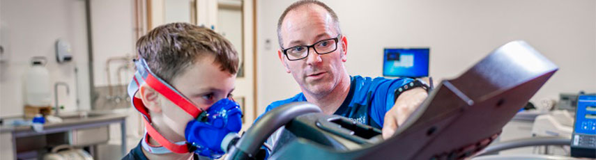 Researcher and young person with mask on doing physical activity