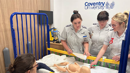 Two student midwives practicing with two plastic babies
