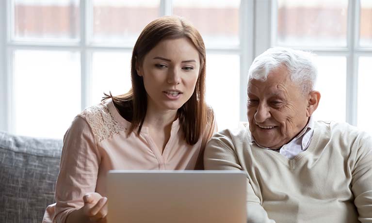 Lady talking to older gentleman by a laptop