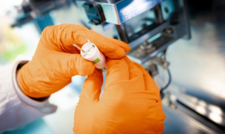 close up of someone with orange gloves inspecting cables in a lab