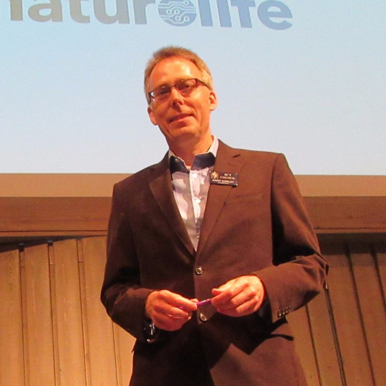 Photo of Andrew Cobley wearing a suit and standing on a stage