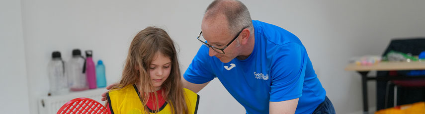 Professor Mike Duncan teaching a child how to play tennis