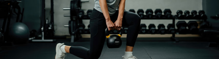 Fitness enthusiast performing lunges with kettlebell in gym