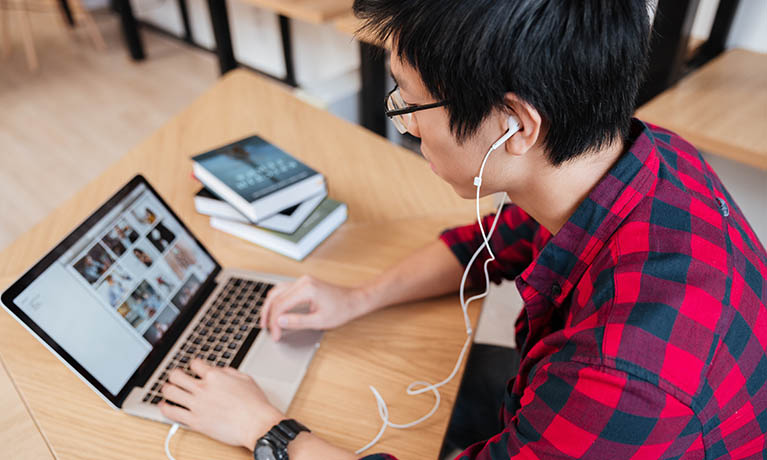 a man leaning over a laptop wearing headphones