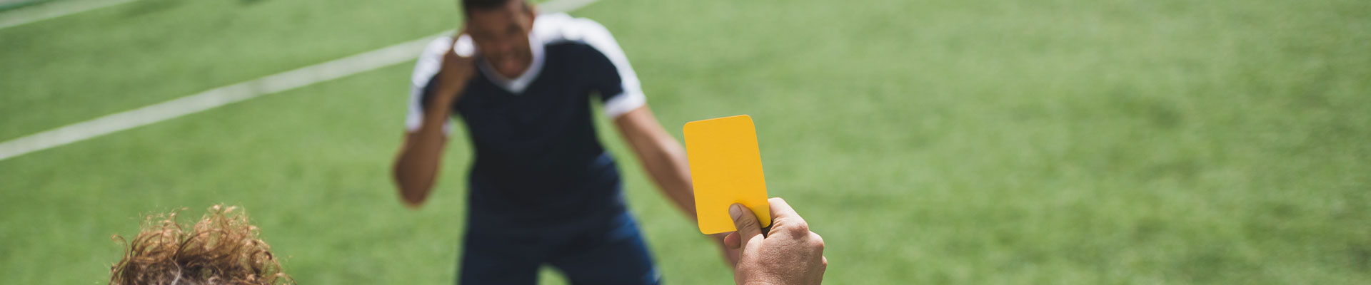 Back view of football referee showing yellow card to players during game