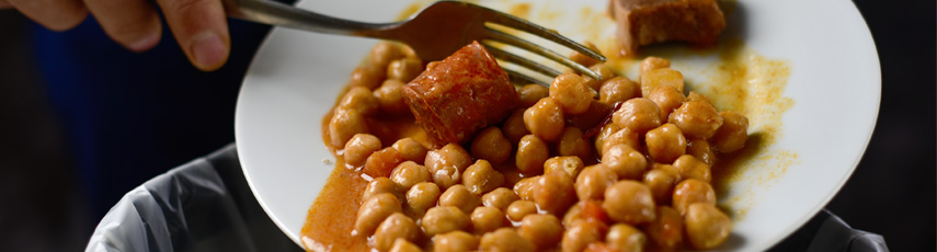 chickpeas and sausage being scraped off a plate into the bin